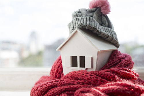 Photo of a small toy house wearing a hat and scarf